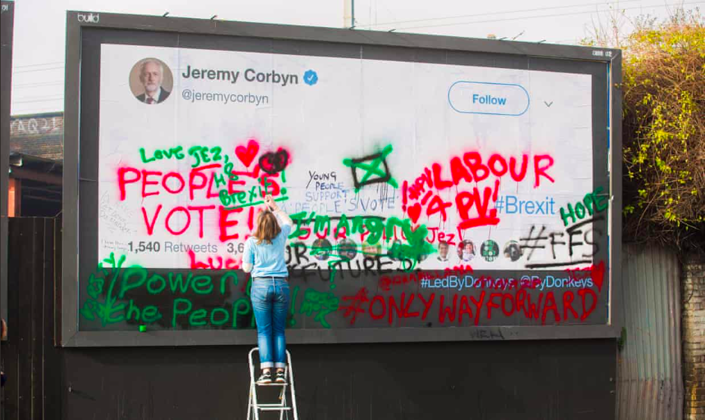 Image of a billboard being covered in graffiti