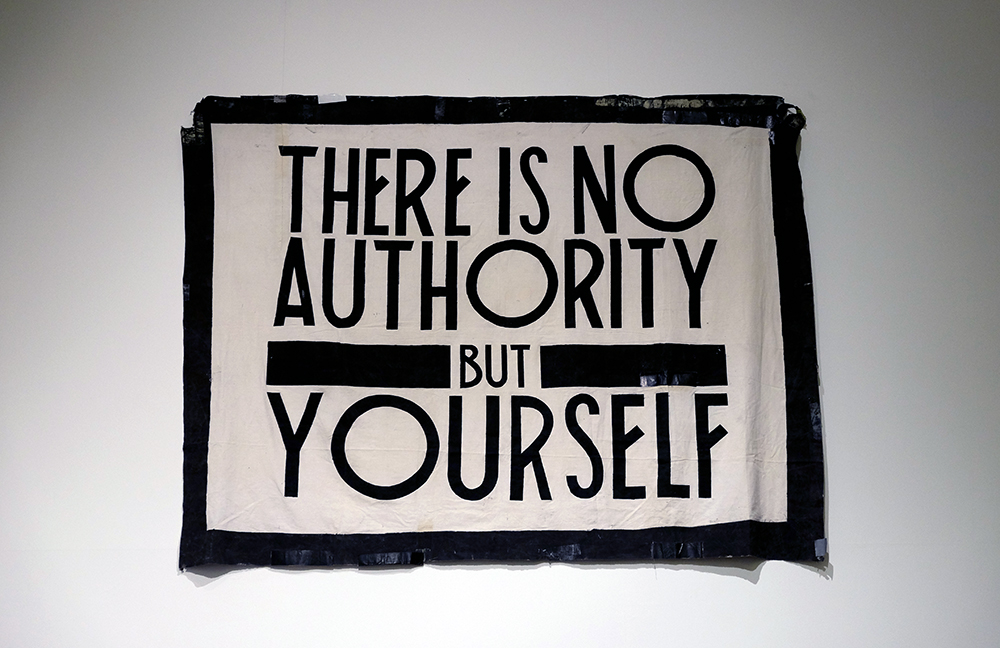 A black and white concert backdrop hung on a wall with the text: There is no authority but yourself