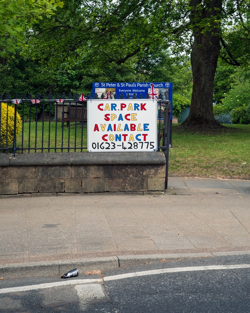 A handwritten colourful sign advertising car park space available with a phone number.