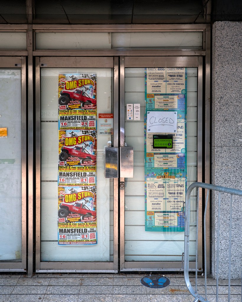 A shop front with its glass doors flyposted with adverts.