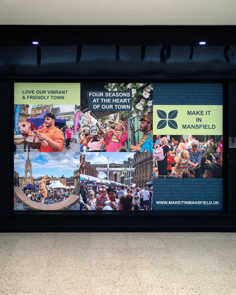 A sign with many photographs of people and text, some of which reads: Make It In Mansfield, and Love Our Vibrant & Friendly Town.