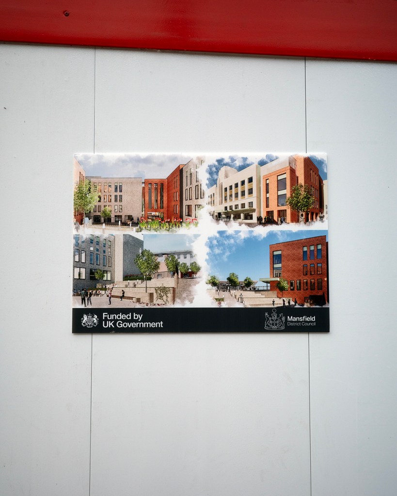 Four drawings of buildings and street scenes on a hoarding.