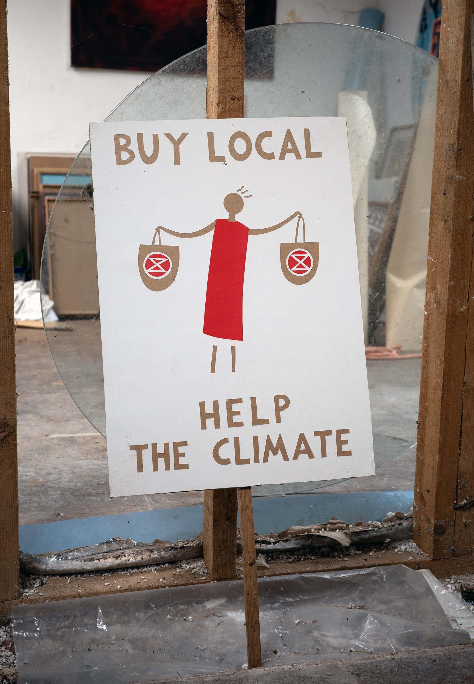 A placard with a woman carrying bags and the words: Buy Local help The Climate.