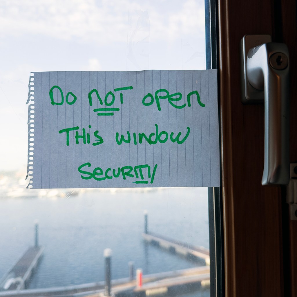 A piece of paper on a window with green felt tip pen reading: do not open this window security