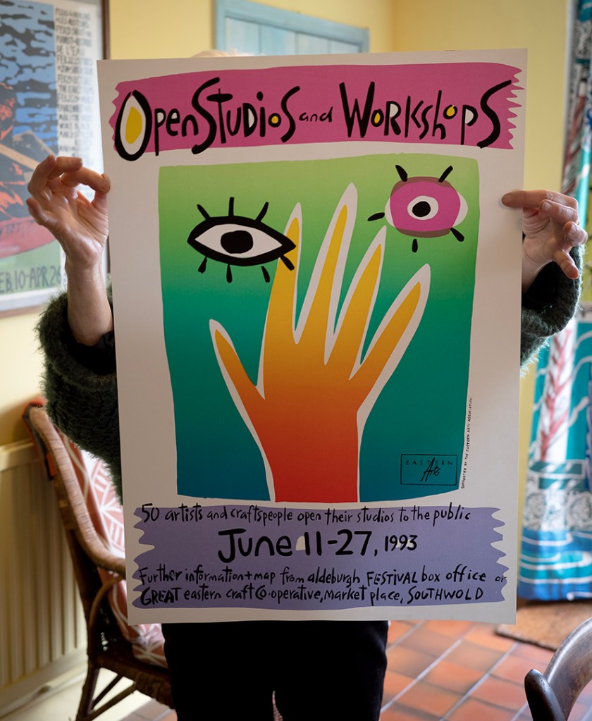 A person holding a poster. The poster depicts an illustration of a hand, an eye and the sun. The top of the poster reads: Open Studios and Workshops.