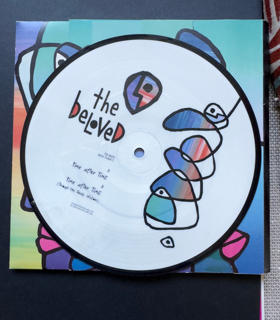 A vinyl single in white, with The Beloved written on it and a squiggly line.